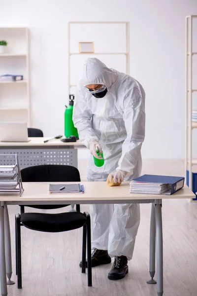 Jovem empreiteiro masculino desinfetando escritório durante pandemia — Fotografia de Stock