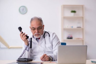 Klinikte çalışan yaşlı erkek doktor.