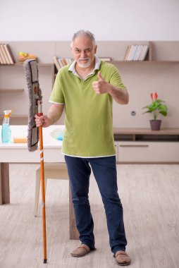 Yaşlı adam evi temizliyor.