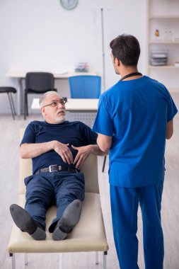Yaşlı adam genç erkek doktoru ziyaret ediyor.