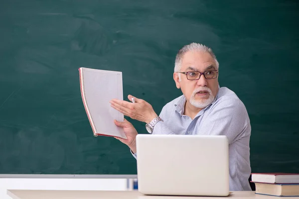 Öreg férfi tanár a zöld tábla előtt — Stock Fotó