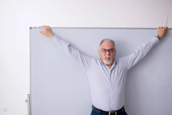 Yaşlı erkek öğretmen beyaz tahtanın önünde. — Stok fotoğraf