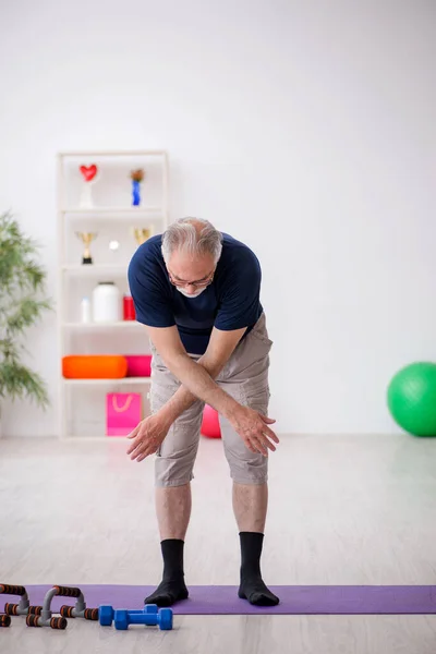 Old man doing sport exercises indoors