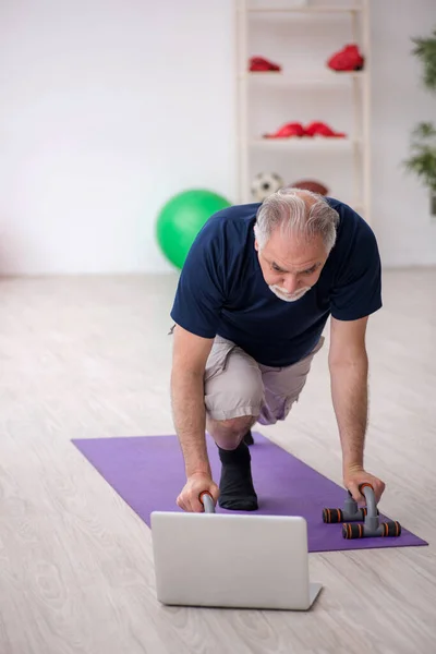 Old man doing sport exercises indoors