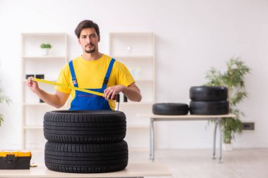 Atölyede lastiği olan genç bir erkek tamirci.