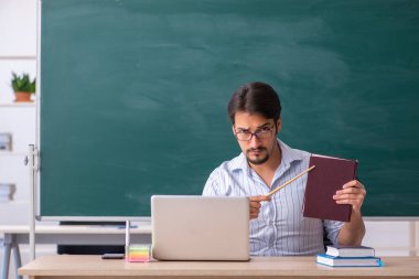 Tahtanın önündeki genç erkek öğretmen.