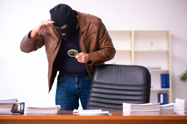 Junger Mann mit Sturmhaube stiehlt Informationen aus Büro — Stockfoto