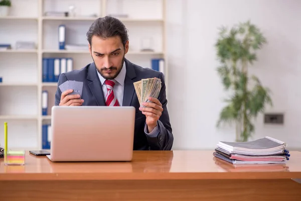 Young male employee playing cards at workplace