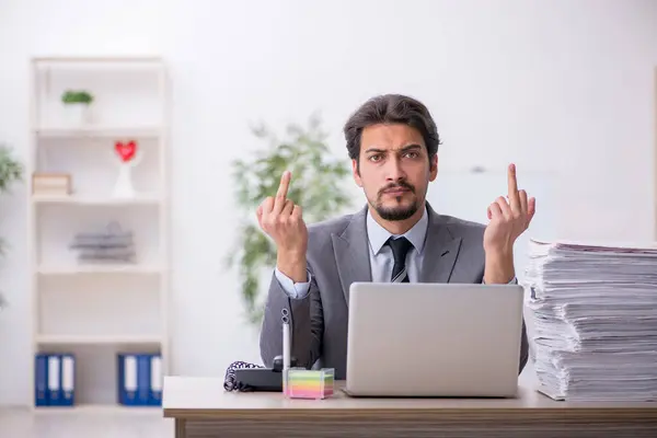 Young male employee and too much work in the office — Stock Photo, Image