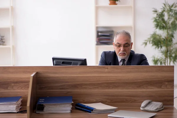 İş yerinde oturan yaşlı erkek çalışan. — Stok fotoğraf