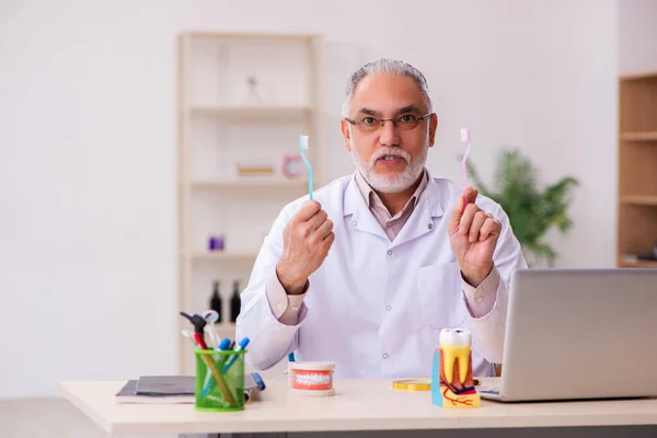 Oude mannelijke tandarts werkt in de kliniek — Stockfoto