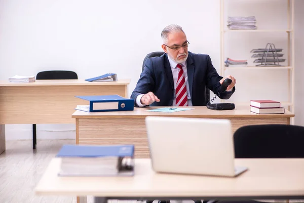 Oude zakenman werknemer zit in het kantoor — Stockfoto