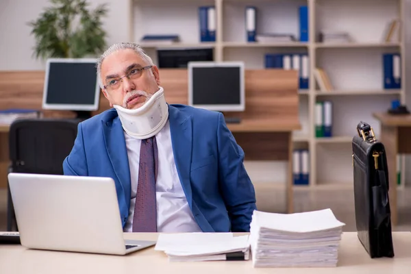 Old businessman employee after accident working in the office