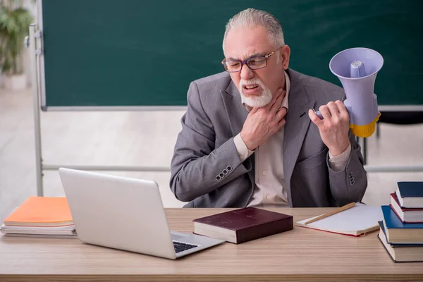 Starý učitel drží megafon před tabulí — Stock fotografie