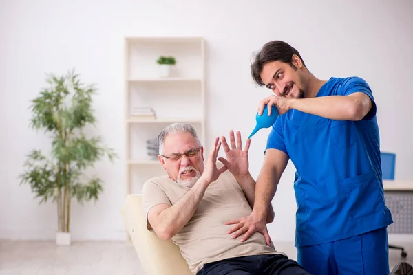 Vieux patient de sexe masculin visitant jeune médecin gastro-entérologue — Photo