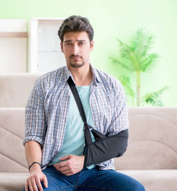 Eli yaralı genç bir öğrenci kanepede oturuyor.