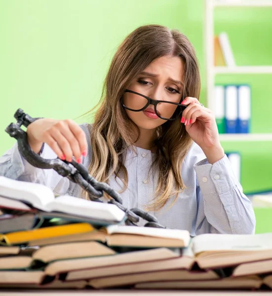 Young female student chained to the desk and preparing for exams — Stock Photo, Image