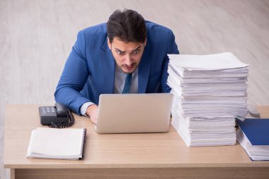 Ofisteki aşırı işten memnun olmayan genç bir erkek işçi.