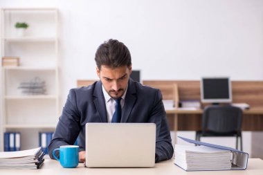 Genç erkek çalışan işyerinde oturuyor.