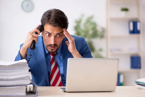 Jonge mannelijke werknemer ongelukkig met overmatig werk in het kantoor — Stockfoto