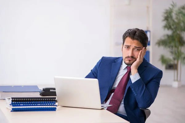 Jovem funcionário masculino infeliz com excesso de trabalho no escritório — Fotografia de Stock