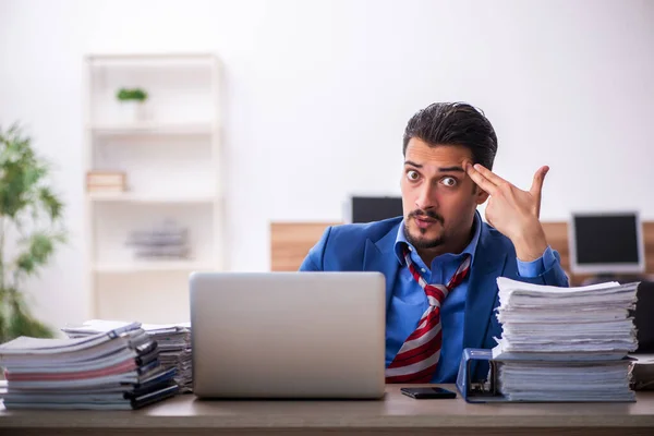 Giovane dipendente maschio infelice con un lavoro eccessivo sul posto di lavoro — Foto Stock