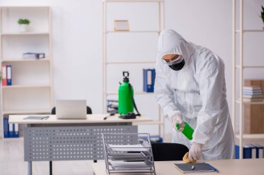 Young male contractor disinfecting office during pandemic
