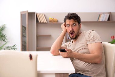 Genç adam ve evde bir sürü hamamböceği var.