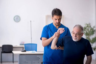 Yaşlı adam genç erkek doktoru ziyaret ediyor.