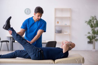 Yaşlı adam genç erkek doktoru ziyaret ediyor.