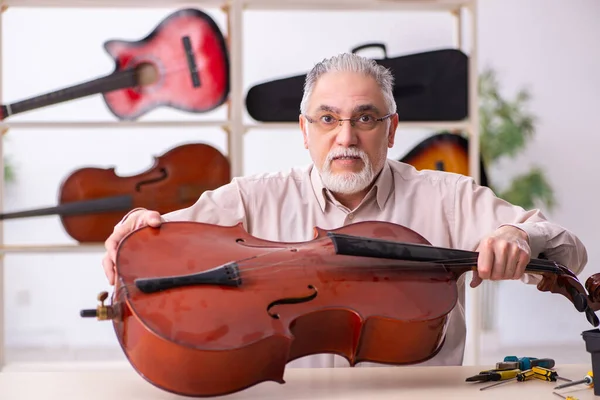 Oude mannelijke reparateur repareert muziekinstrumenten op het werk — Stockfoto