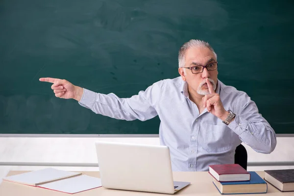 Vieux professeur masculin en face de la planche verte — Photo