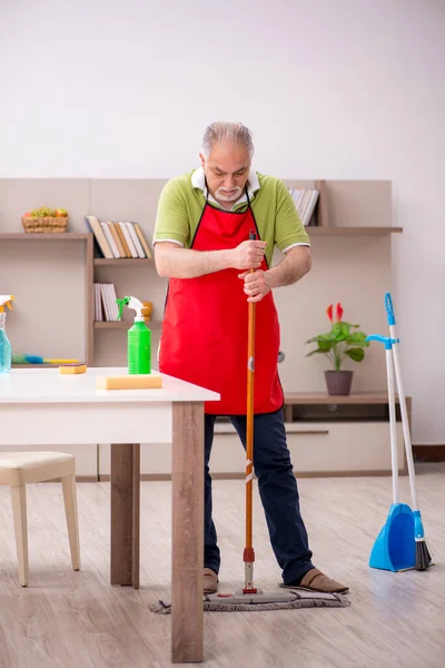 Oude man die het huis schoonmaakt — Stockfoto