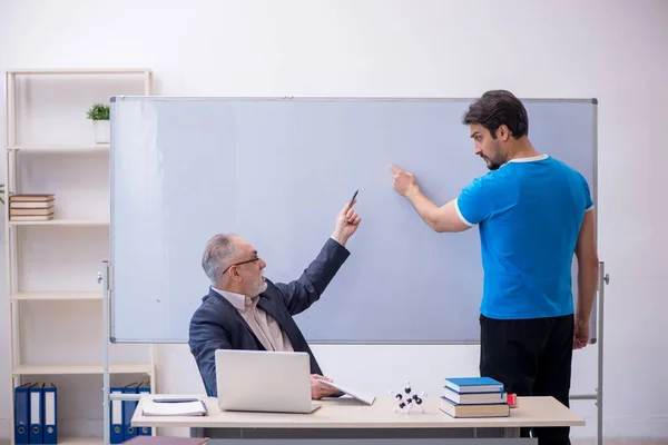 Velho professor e jovem estudante do sexo masculino na frente do quadro branco — Fotografia de Stock