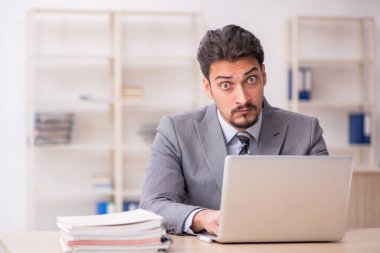 Ofisteki aşırı işten memnun olmayan genç bir erkek işçi.