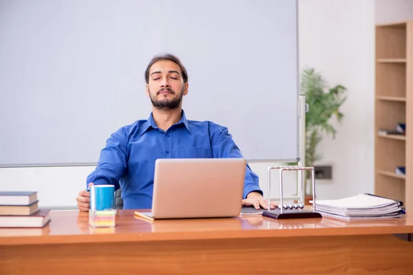 Young male teacher physicist sitting in the classroom — Stock Photo, Image