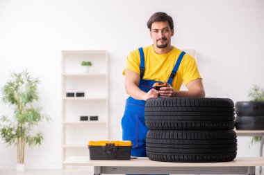 Atölyede lastiği olan genç bir erkek tamirci.