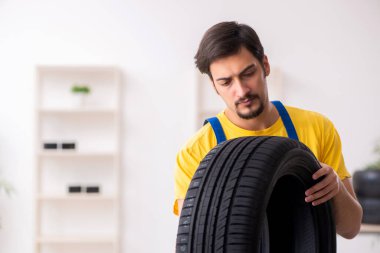 Atölyede lastiği olan genç bir erkek tamirci.