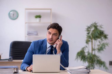 Genç erkek çalışan ofiste oturuyor.