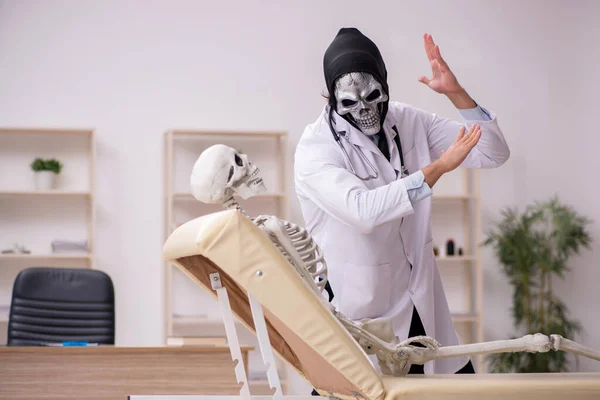 Duivelse dokter onderzoekt skelet patiënt — Stockfoto