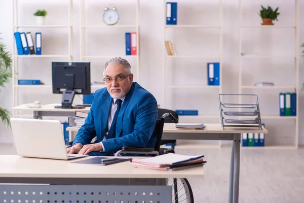 Ancien employé masculin en fauteuil roulant assis dans le bureau — Photo