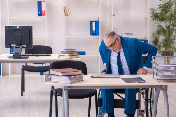 Ancien employé masculin en fauteuil roulant assis dans le bureau — Photo