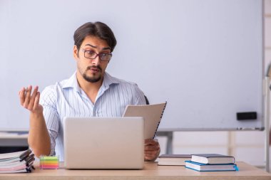 Genç erkek öğretmen beyaz tahtanın önünde.