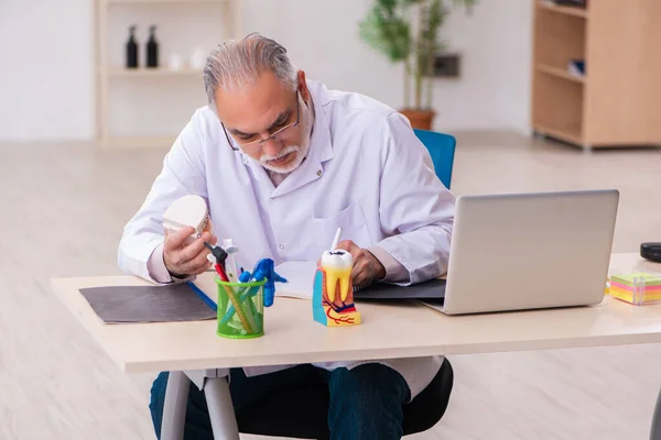 Old male dentist working in the clinic — Stock Photo, Image