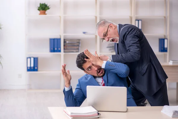 Viejo jefe y joven empleado masculino en concepto de intimidación —  Fotos de Stock