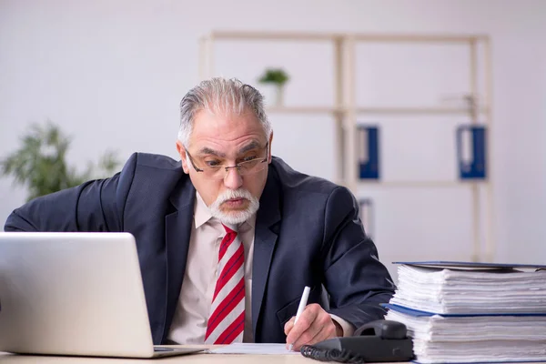 Alte männliche Mitarbeiter sitzen am Arbeitsplatz — Stockfoto