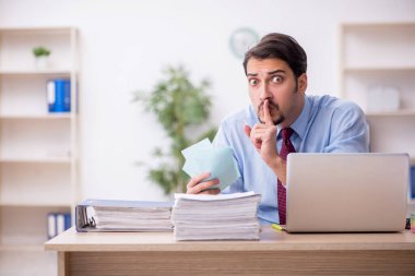 Genç bir erkek çalışan ve ofiste çok fazla iş var.