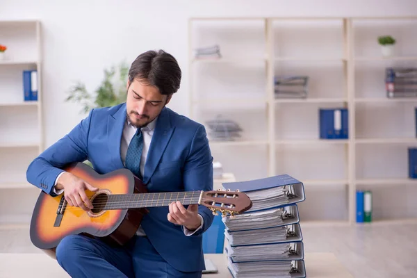 Giovane dipendente di sesso maschile che suona la chitarra sul posto di lavoro — Foto Stock