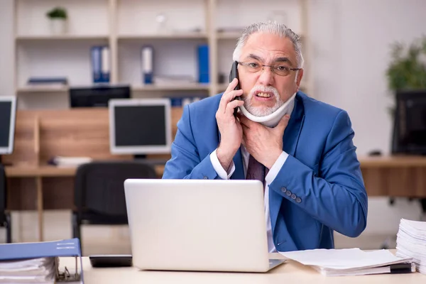 Old businessman employee after accident working in the office