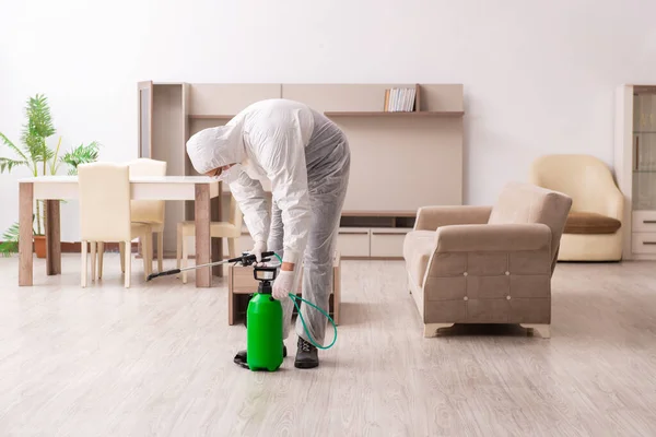 Young male contractor doing pest control at home